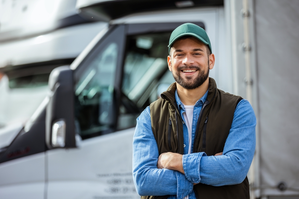 happy JPS Logistique truck driver in front of a logistics and transportation truck